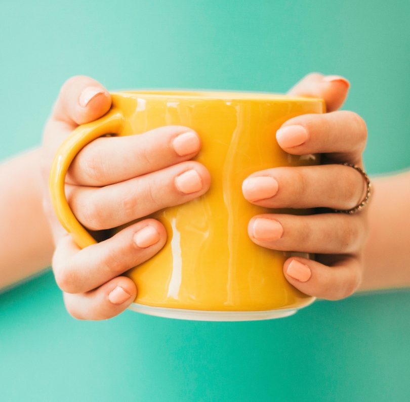hands cupping a yellow mug